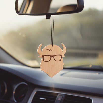 Curious Bison wood ornament hanging from a car rearview mirror, logo shaped wood accessory with bison horns and glasses, Route 66 road trip keepsake