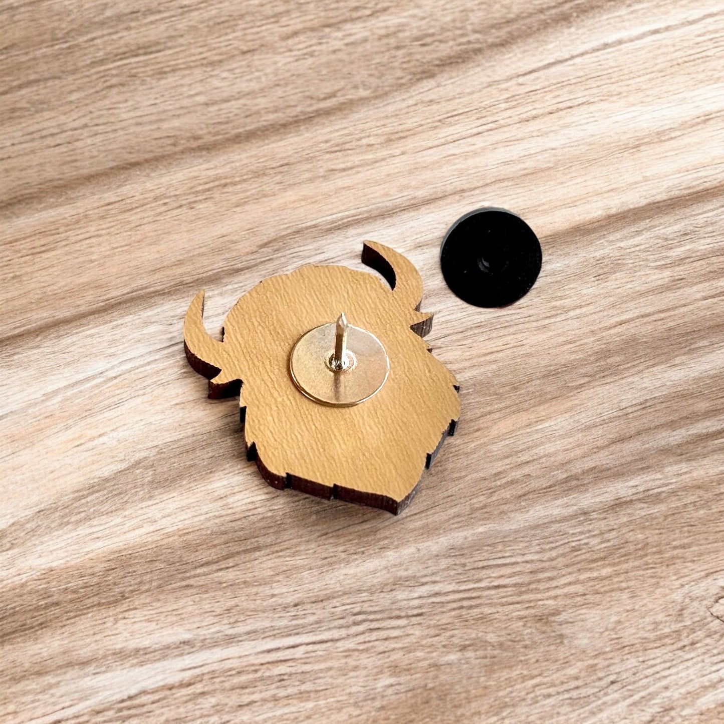 Back of Curious Bison wooden pin showing metal post and black rubber pin back, lightweight wood lapel pin for hats and jackets