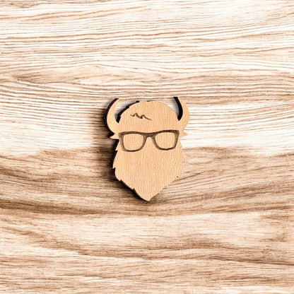 Curious Bison wood pin displayed on wood surface, engraved bison glasses design made from laser cut wood