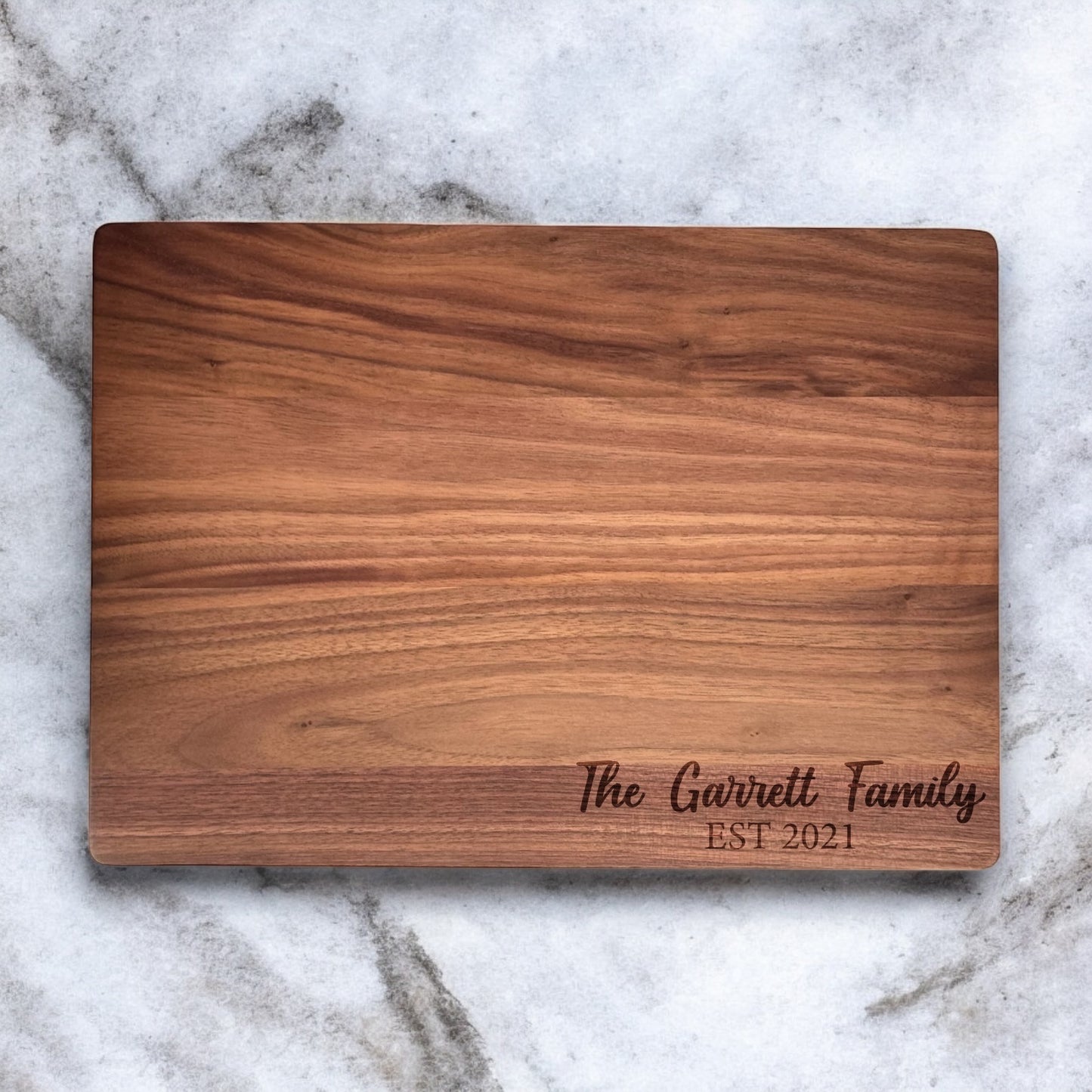 Custom engraved walnut cutting board with family name text, personalized hardwood kitchen board