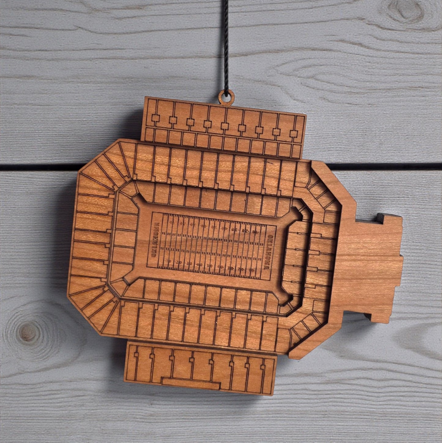 Close up of Gaylord Family Memorial Stadium wooden ornament showing engraved seating sections and layered wood construction, detailed Oklahoma Sooners stadium ornament