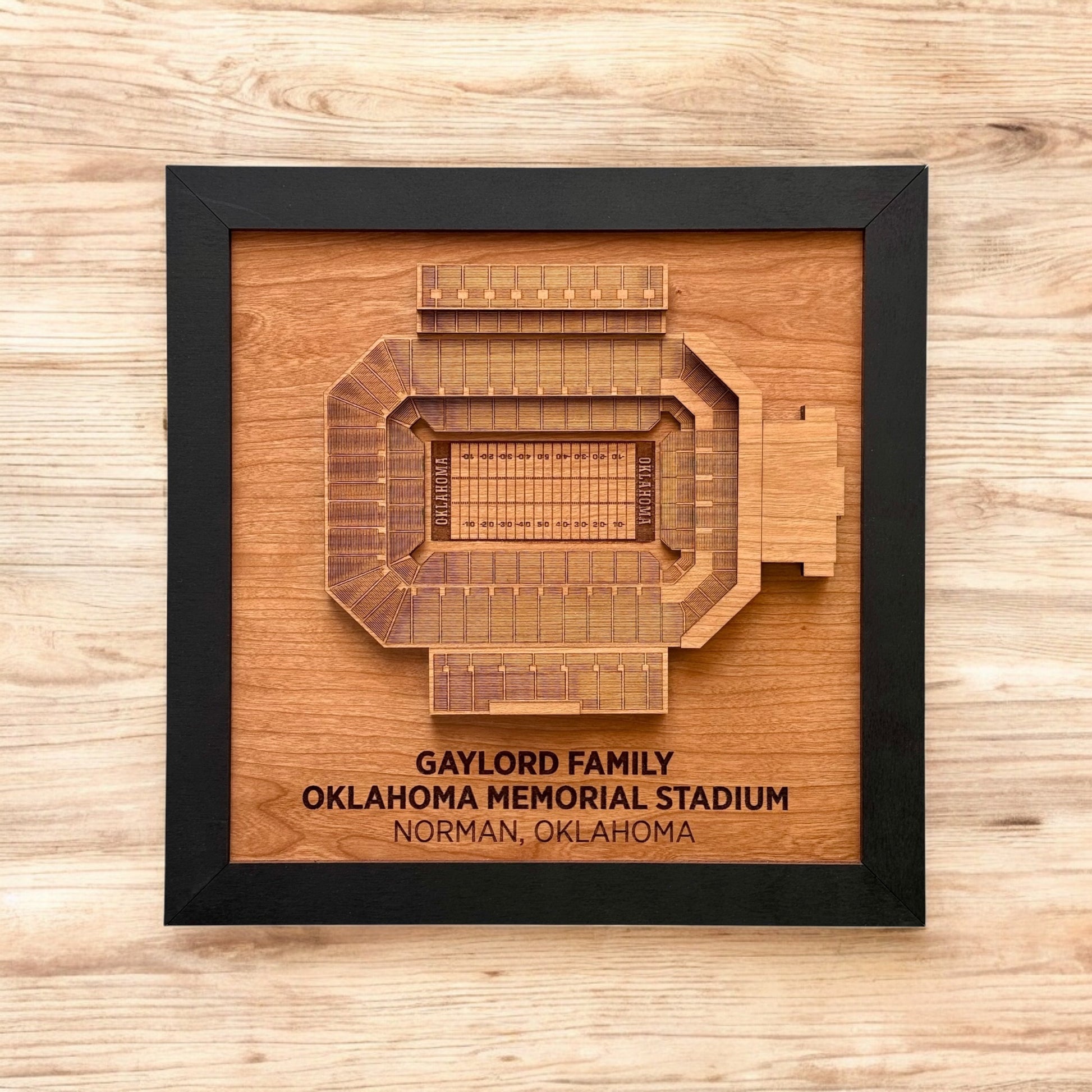 Flat lay view of framed Oklahoma Memorial Stadium wood art on a wood surface
