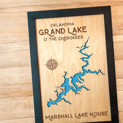 Close up of Grand Lake O’ the Cherokees wood map showing blue lake backing and engraved compass rose
