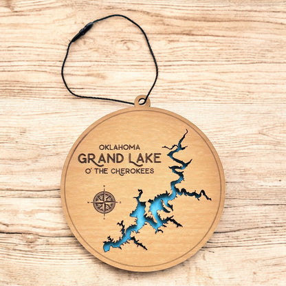Grand Lake layered wood ornament shown on wood surface, round lake map ornament with blue water layer