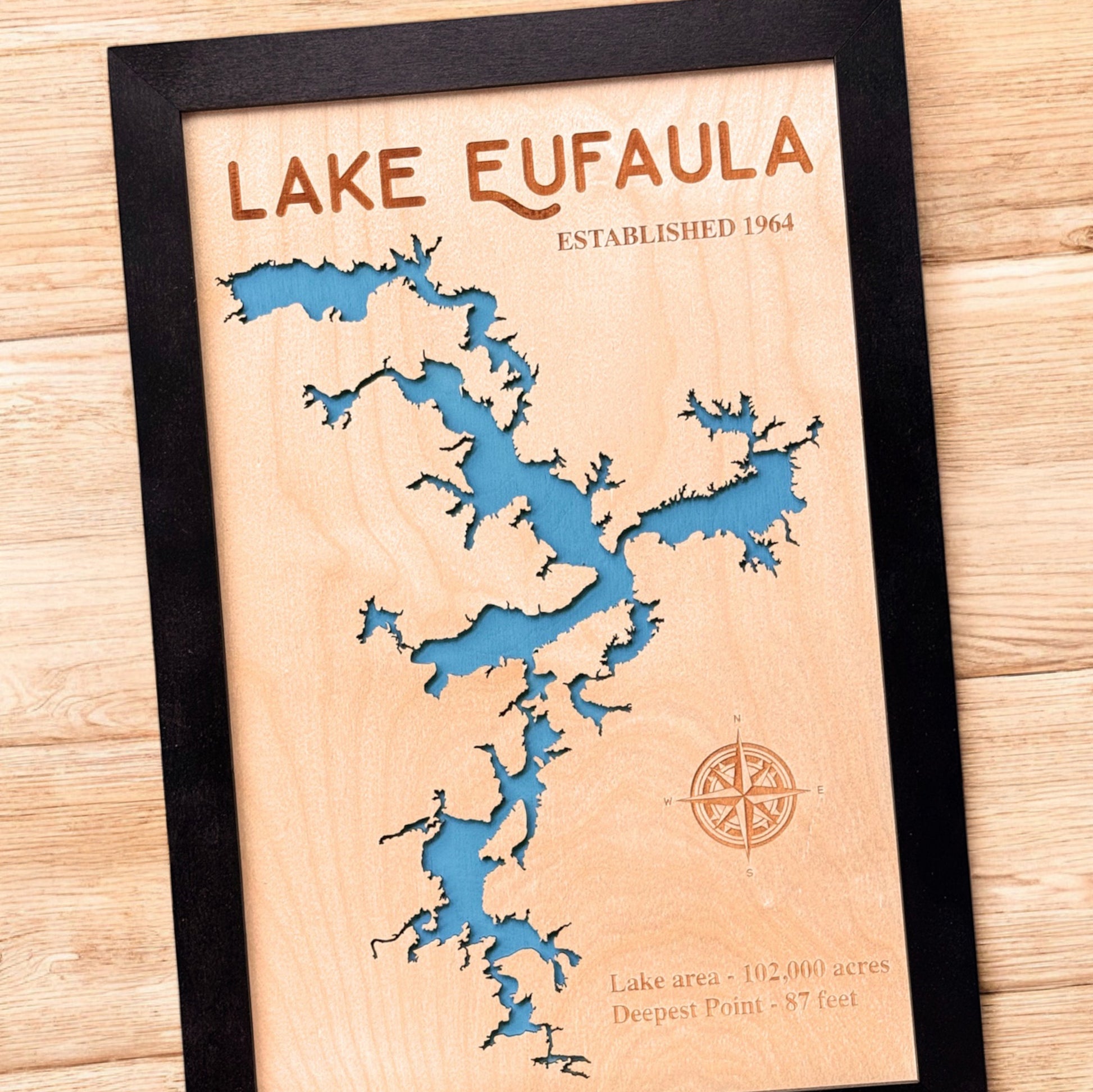 Close up angled view of Lake Eufaula wooden map showing laser cut shoreline, engraved text, and blue layered water detail
