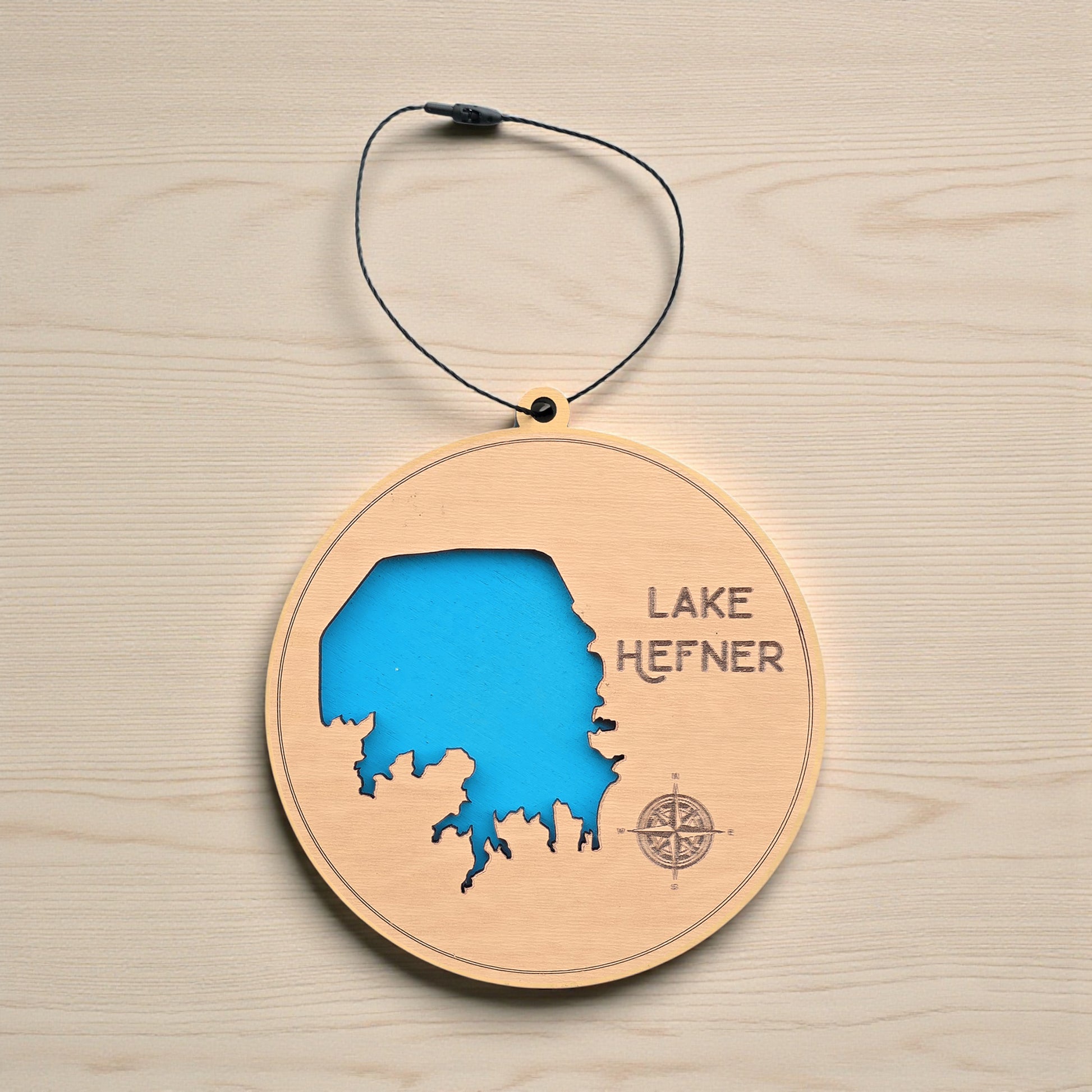 Flat lay of Lake Hefner wooden ornament displaying lake shoreline cutout, engraved name and compass, Oklahoma lake map ornament made from wood