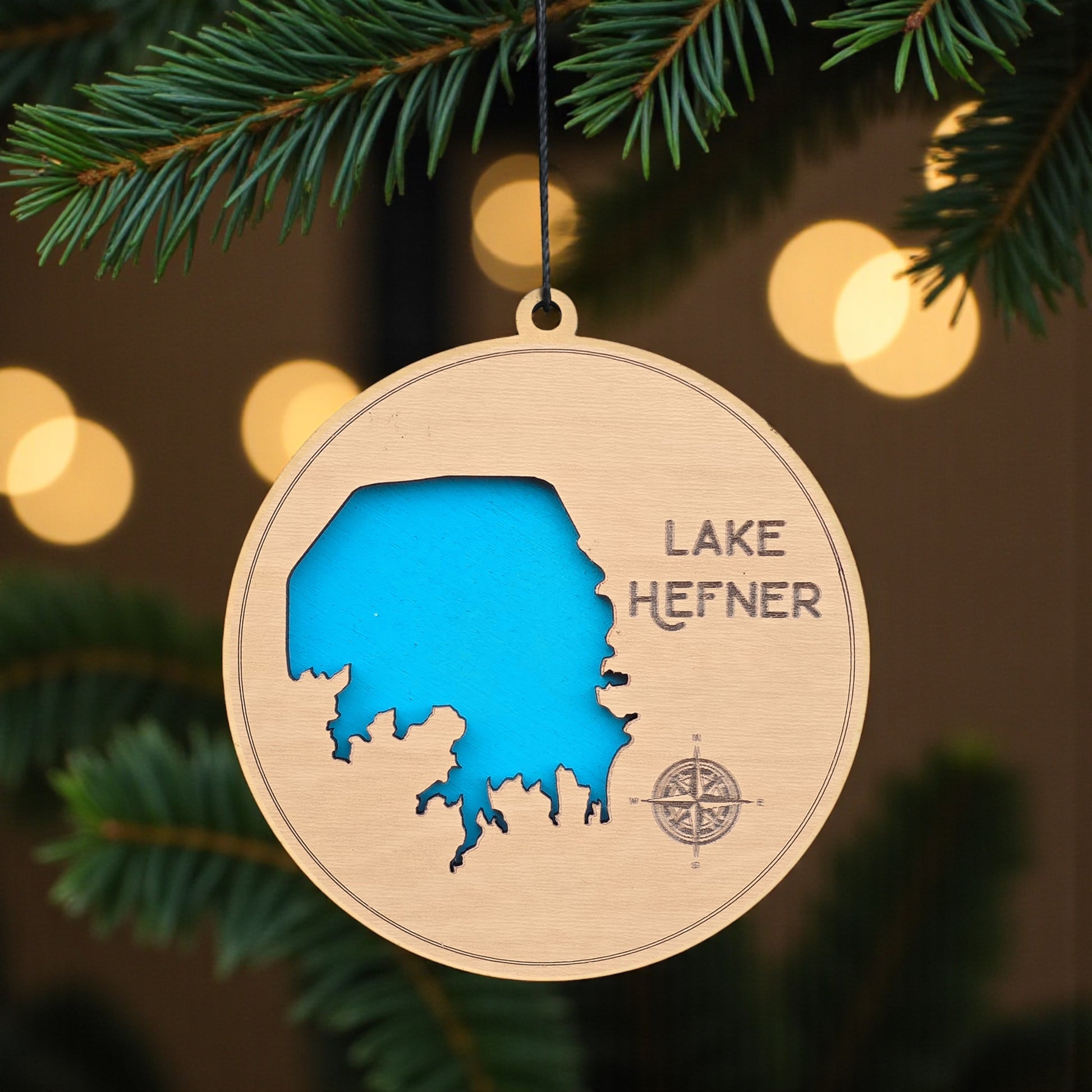 Lake Hefner wooden ornament hanging on evergreen tree, laser cut wood lake map ornament with blue inlay used as Oklahoma City Christmas decor or travel keepsake