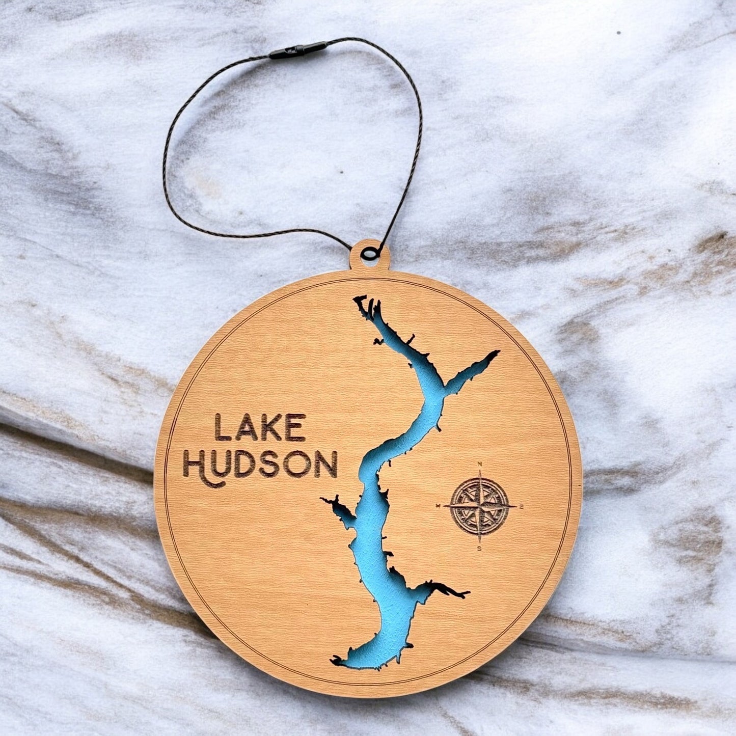 Lake Hudson layered wooden ornament displayed on marble surface showing engraved lake name, compass detail, and blue painted water layer