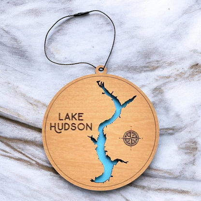 Lake Hudson layered wooden ornament displayed on marble surface showing engraved lake name, compass detail, and blue painted water layer