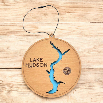 Lake Hudson layered wood ornament shown on wood surface, round lake map ornament with engraved text and blue water detail