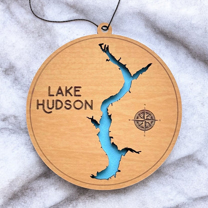 Close up of Lake Hudson wooden map ornament showing laser cut shoreline detail, engraved compass, and painted blue water layer