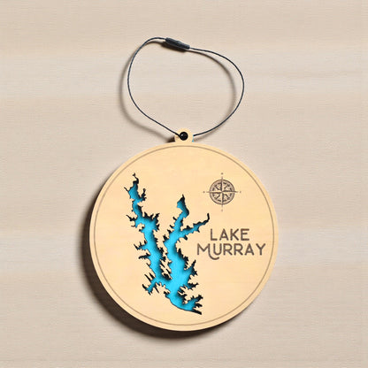 Flat lay of Lake Murray layered wooden ornament showing engraved lake name, compass detail, and blue painted water layer beneath laser cut wood top