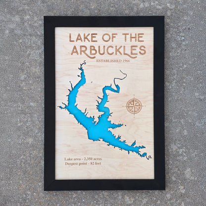 Framed Lake of the Arbuckles wooden map wall art photographed outdoors, layered wood lake map with engraved lake name and compass detail