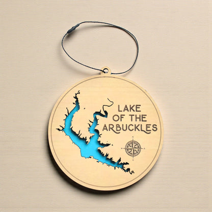 Lake of the Arbuckles wooden ornament hanging on evergreen tree with lights, layered wood lake ornament with engraved lake name and blue water layer