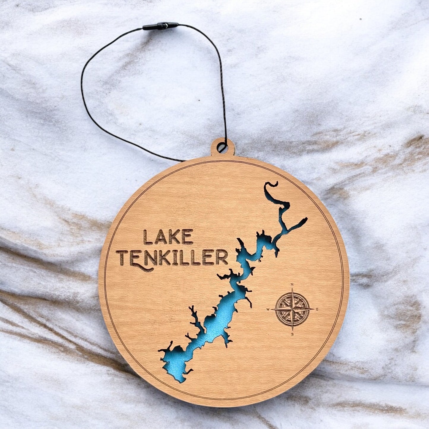 Lake Tenkiller layered wooden ornament displayed on marble surface showing engraved lake name, compass detail, and blue painted water layer.