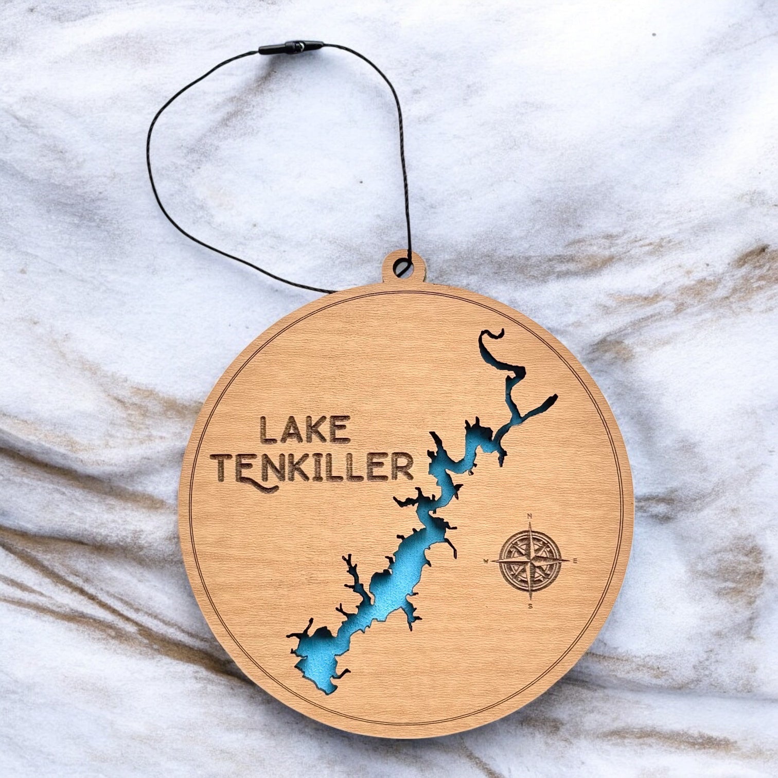 Lake Tenkiller layered wooden ornament displayed on marble surface showing engraved lake name, compass detail, and blue painted water layer.
