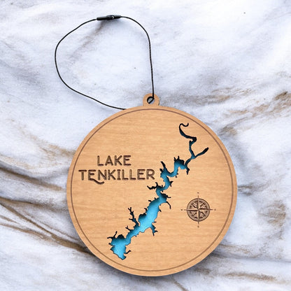Lake Tenkiller layered wooden ornament displayed on marble surface showing engraved lake name, compass detail, and blue painted water layer.