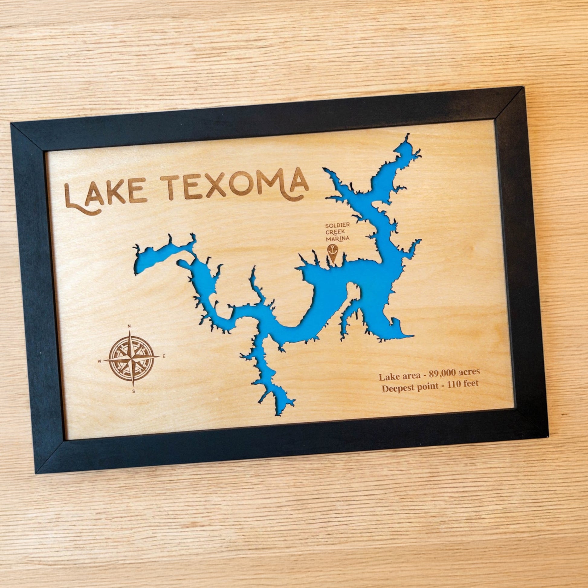 Close up of Lake Texoma wood map showing blue lake backing and engraved compass rose