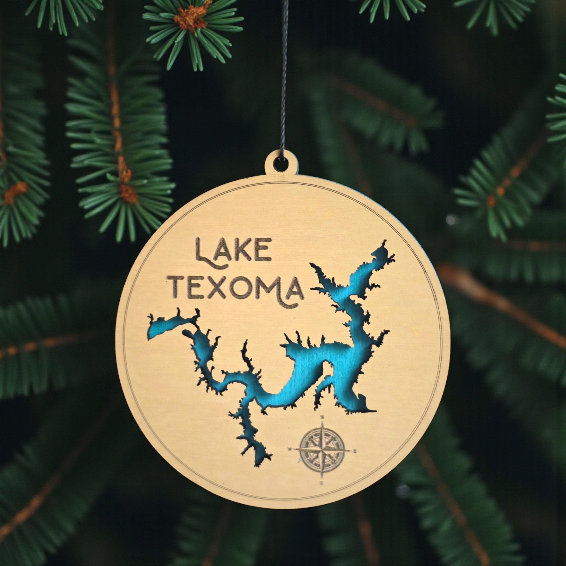 Lake Texoma wooden ornament hanging on evergreen tree with lights, layered wood lake map ornament with blue painted water detail and hanging cord