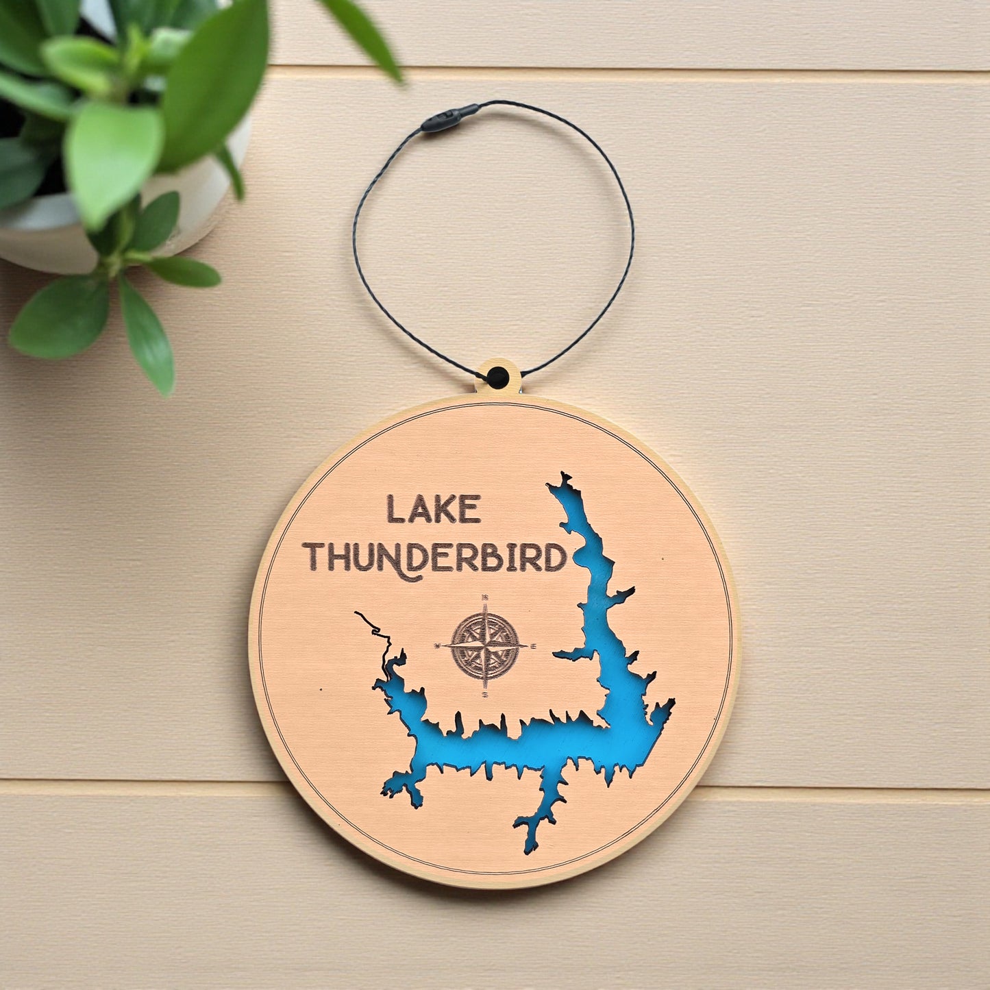 Flat lay of Lake Thunderbird wooden ornament displaying detailed lake shoreline cutout, engraved name and compass, Oklahoma lake map ornament made from wood
