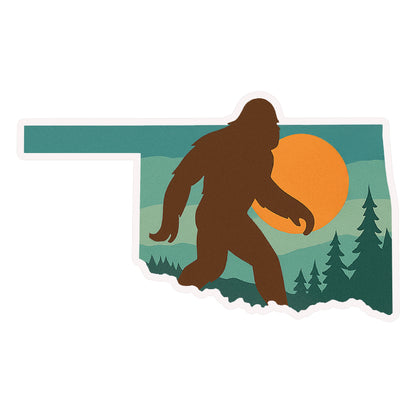 Oklahoma Bigfoot vinyl sticker in state shape featuring Sasquatch silhouette walking through pine trees with sunset background, die cut souvenir sticker for Oklahoma travel and outdoor fans