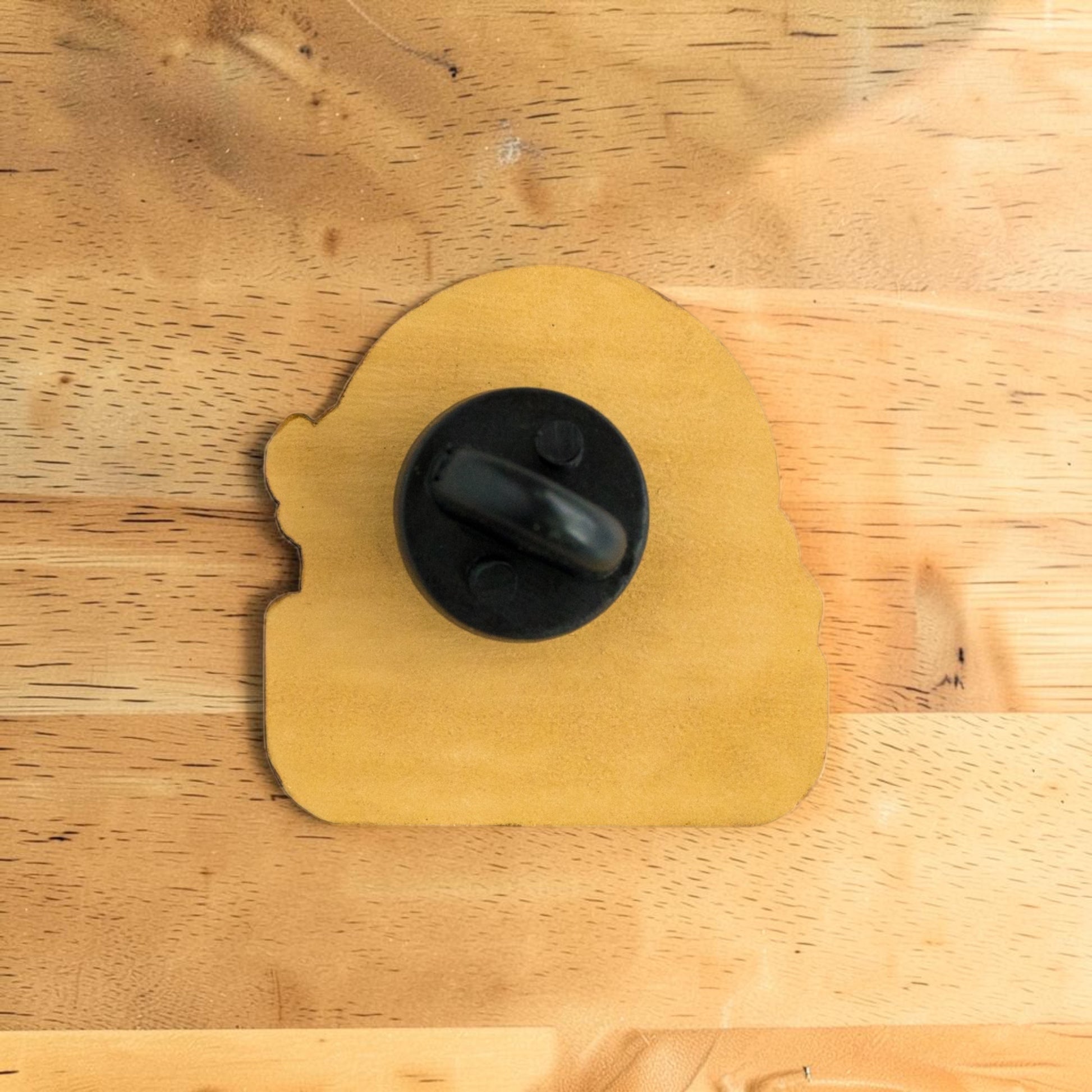 Back side of Oklahoma bison wooden lapel pin showing secure rubber backing on Eco Wood Birch souvenir pin displayed on wood surface