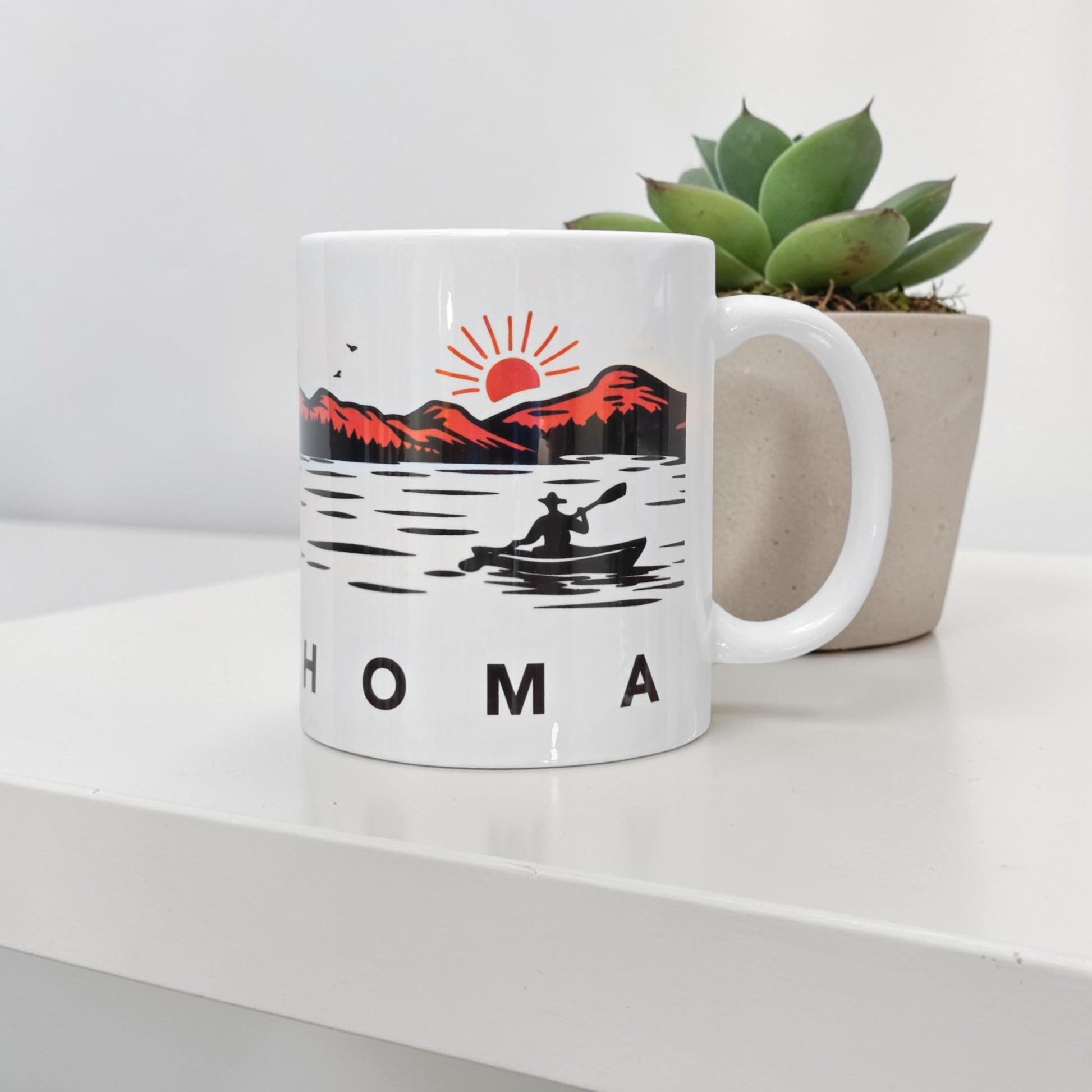 Oklahoma wildlife 11oz coffee mug featuring canoe paddler on lake at sunrise with mountain silhouettes and forest scene, Oklahoma travel souvenir mug