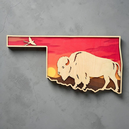 Oklahoma state shaped wall art with layered sunset design, large bison silhouette, and Scissortail Flycatcher displayed against gray wall background for Oklahoma souvenir and western decor