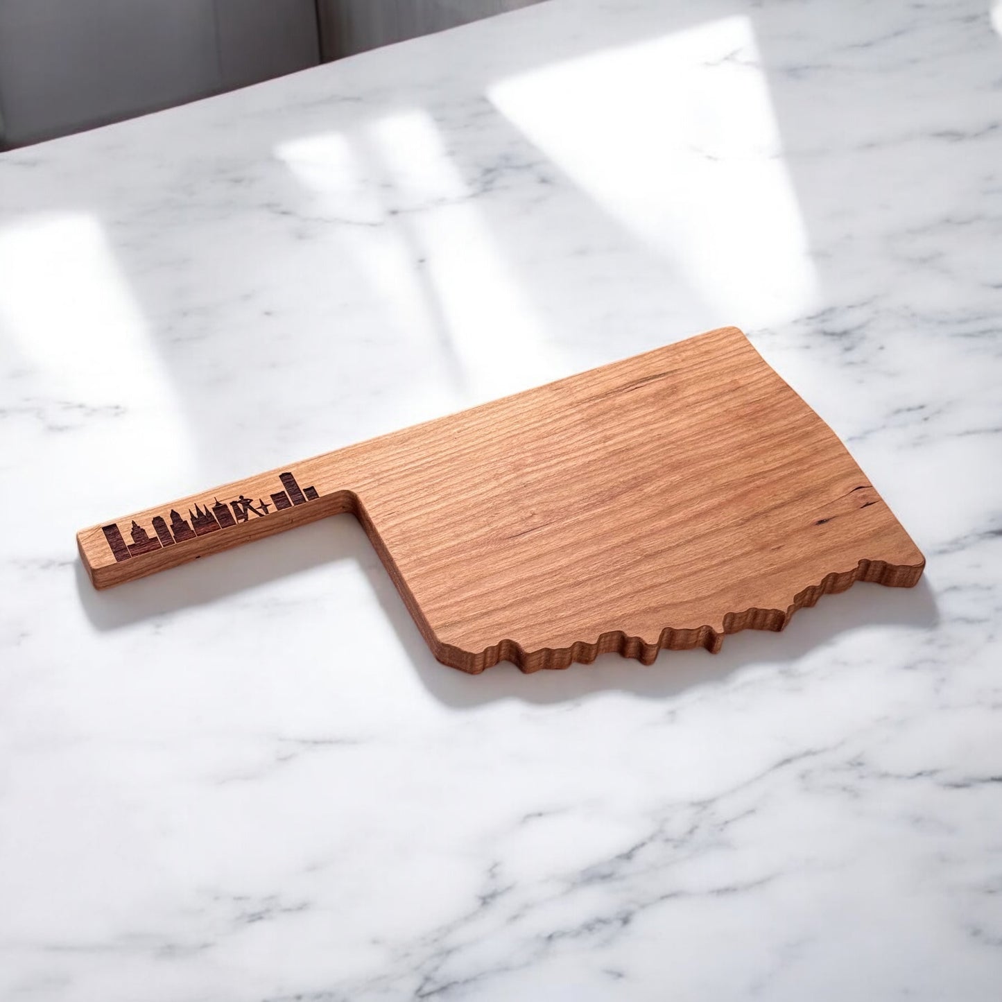 Oklahoma cherry wood charcuterie board displayed on marble countertop showing serving size and Tulsa skyline engraving
