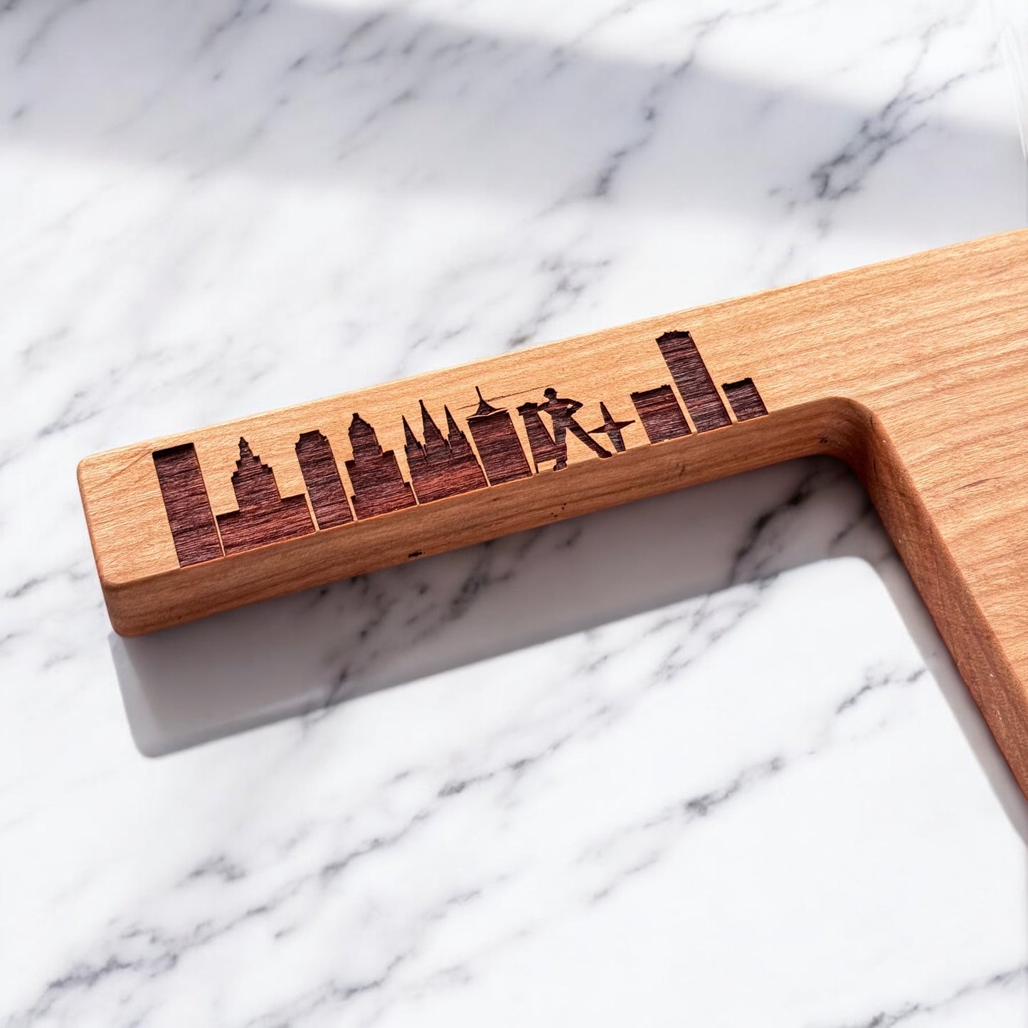 Close up of Tulsa skyline engraving on Oklahoma shaped cherry wood charcuterie board handle showing wood grain and laser detail