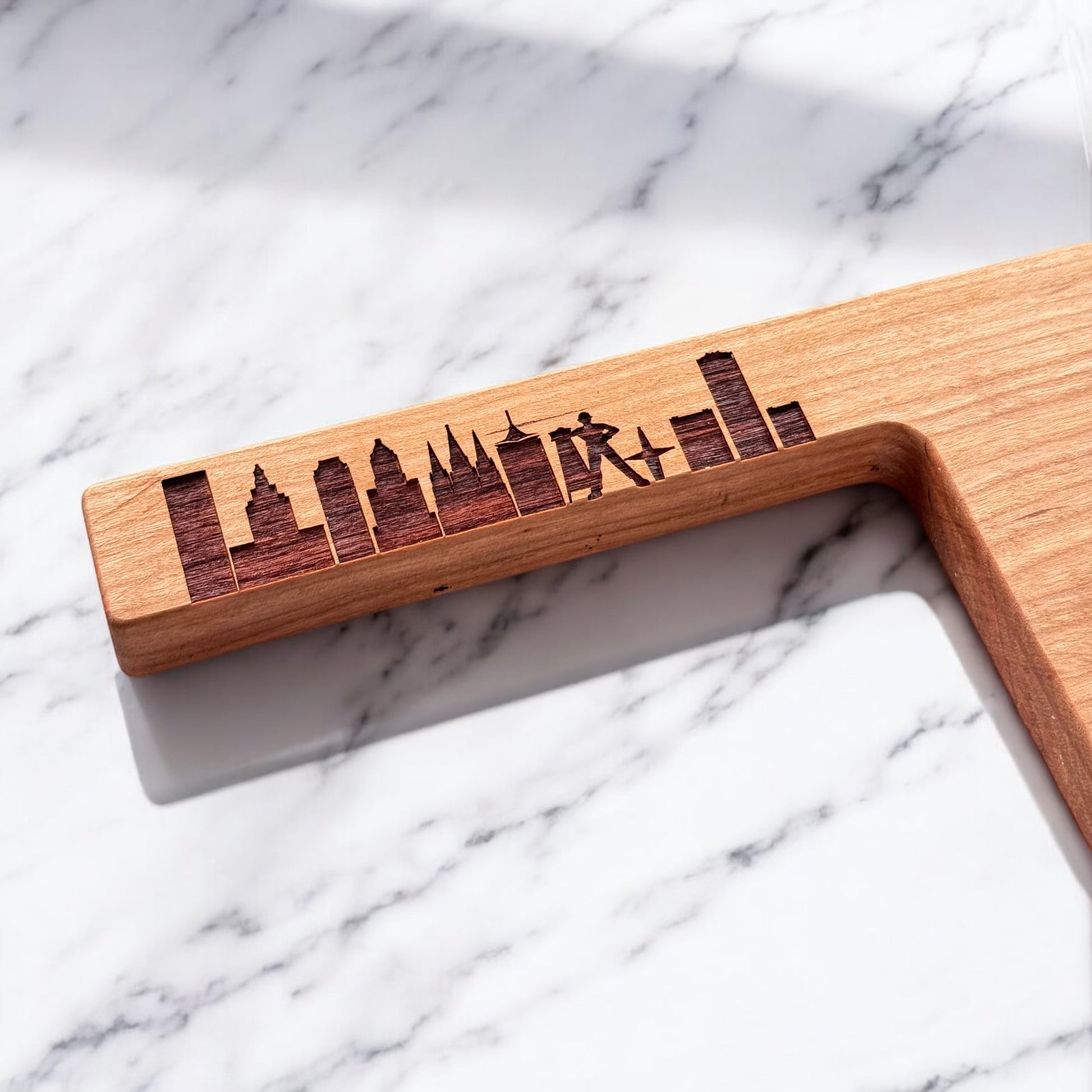 Close up of Tulsa skyline engraving on Oklahoma shaped cherry wood charcuterie board handle showing wood grain and laser detail