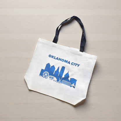Woman carrying large Oklahoma City tote bag with skyline design, photographed downtown near Skydance Bridge.