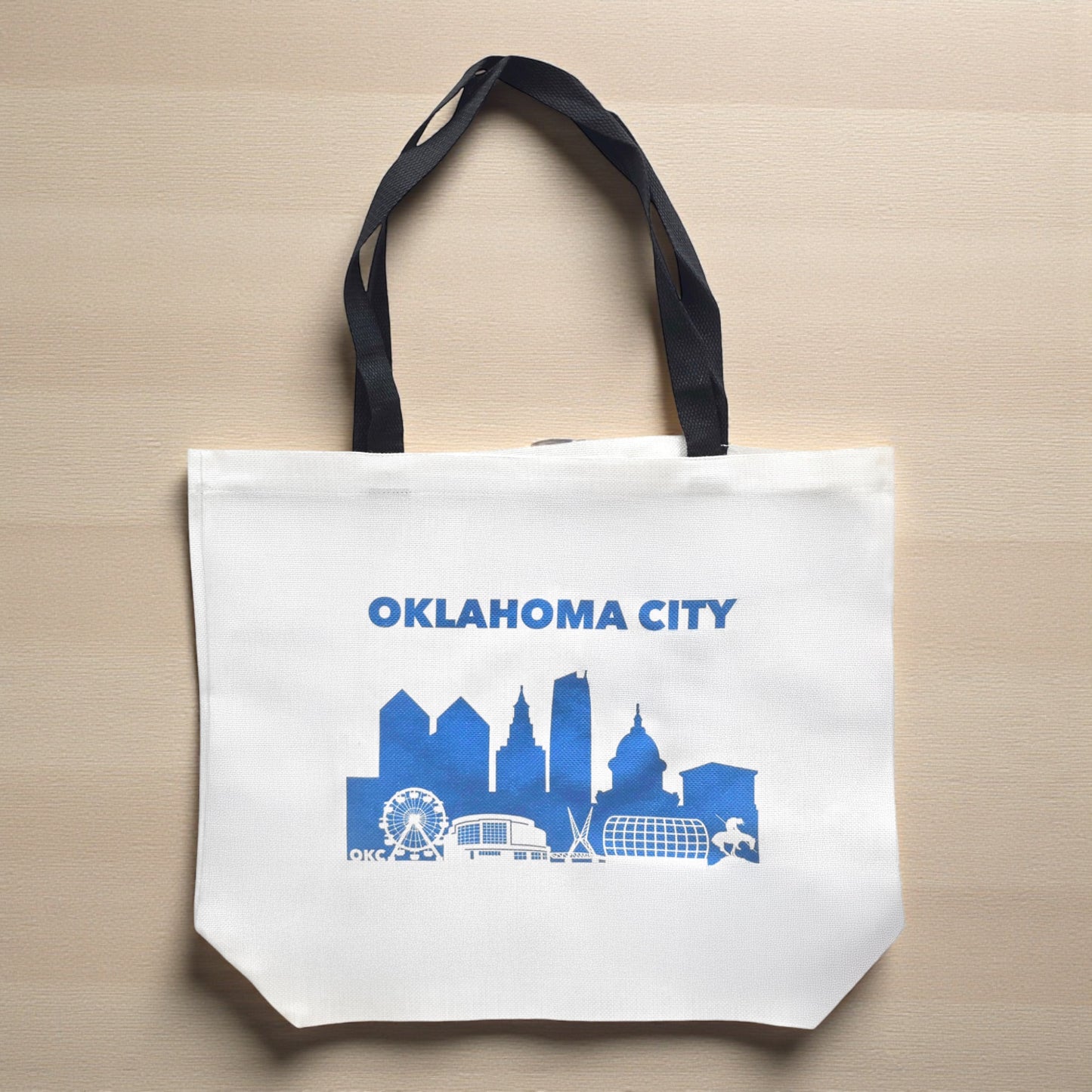 Flat lay of Oklahoma City blue skyline tote bag on neutral surface showing printed OKC city design and canvas texture