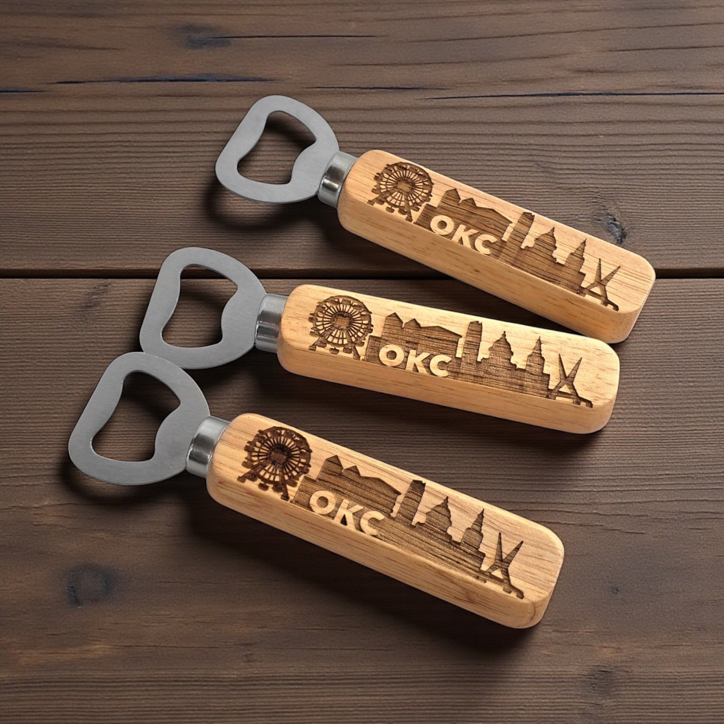 Close-up of engraved OKC skyline wooden bottle openers featuring Skydance Bridge and Wheeler Ferris Wheel design, Oklahoma souvenir gift.