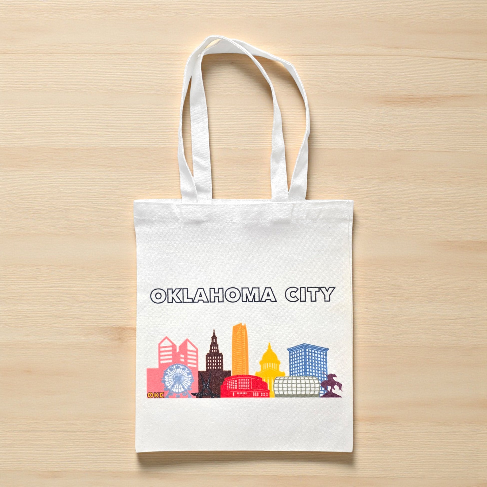 Small Oklahoma City pride skyline tote bag flat lay on wood surface, compact reusable OKC pride tote
