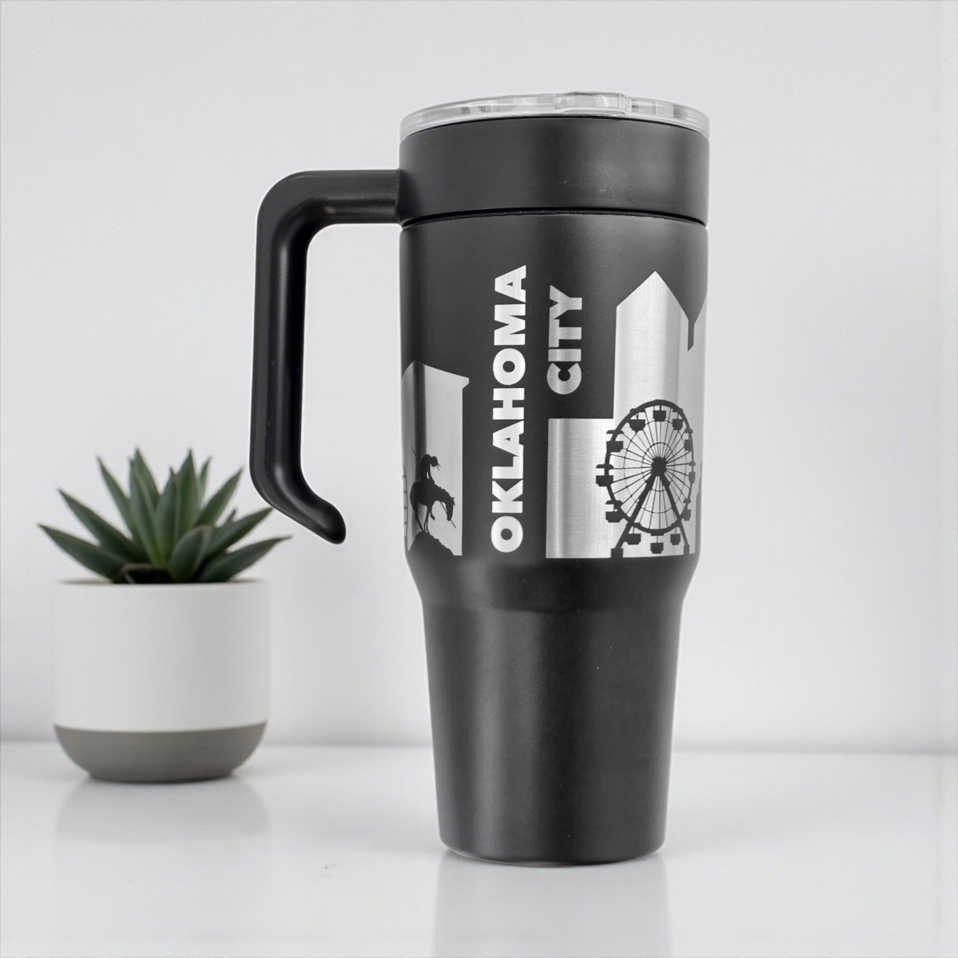 Black Oklahoma City skyline 30oz tumbler with handle attached showing engraved city skyline design, stainless steel Oklahoma City travel mug