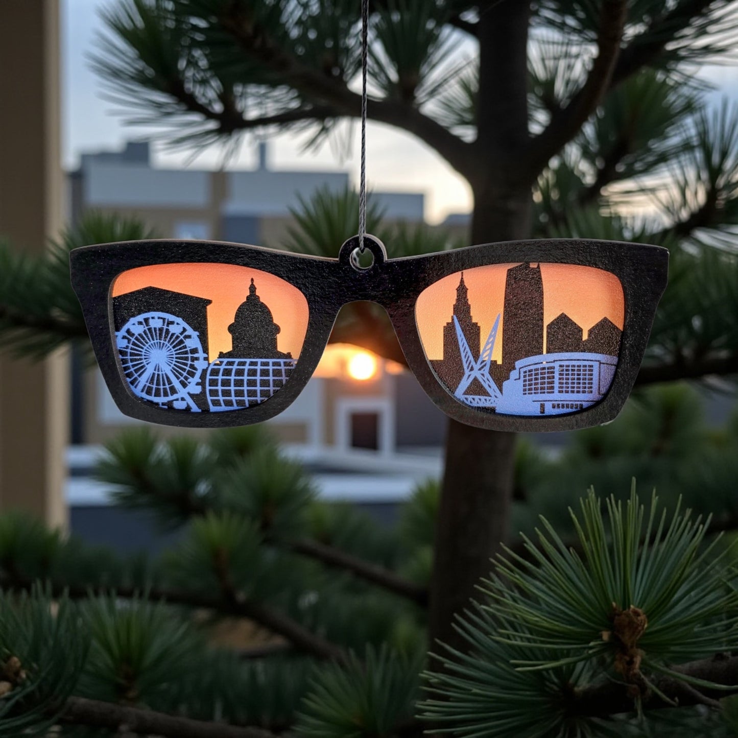 Oklahoma City skyline sunglasses ornament hanging on a tree branch with sunset reflection, Oklahoma Route 66 souvenir decoration.