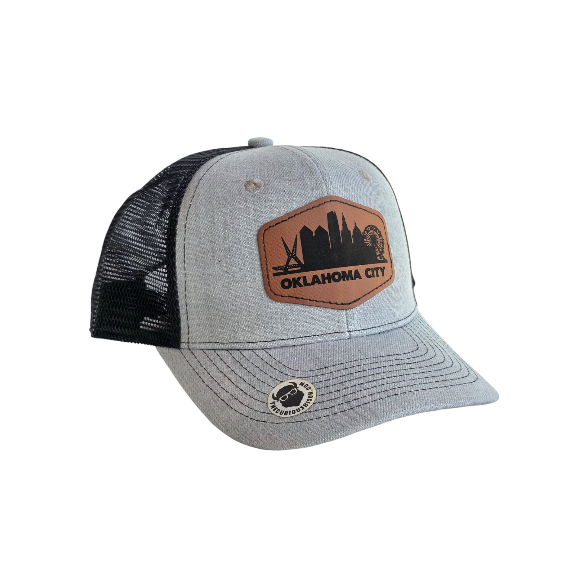 Oklahoma City skyline trucker hat with gray front panel and black mesh back, engraved leatherette patch with city skyline design, Oklahoma City souvenir hat on white background