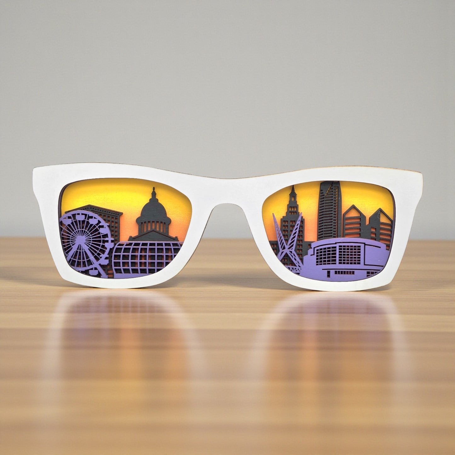 White Oklahoma City skyline sunglasses wall art resting on wooden table, layered city skyline decor piece with sunset style background