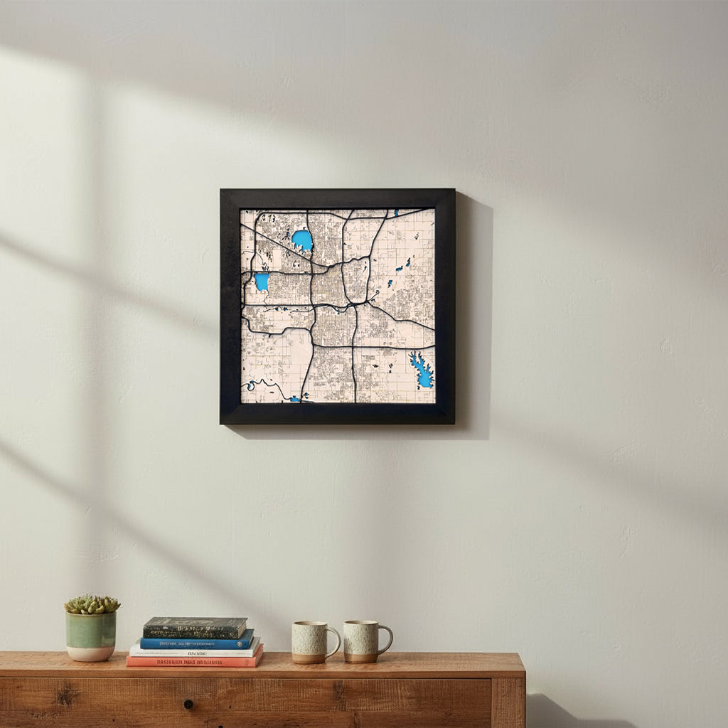 Oklahoma City wooden map wall art displayed on a living room wall above a console table, framed square city map decor showing streets and waterways, Oklahoma City gift idea