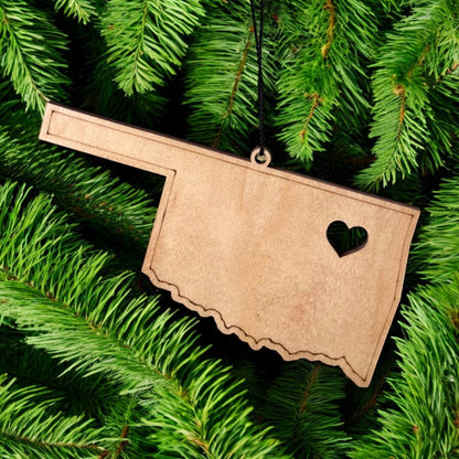 Oklahoma heart wooden ornament hanging on evergreen tree, state shaped laser cut wood ornament used as Oklahoma Christmas decor