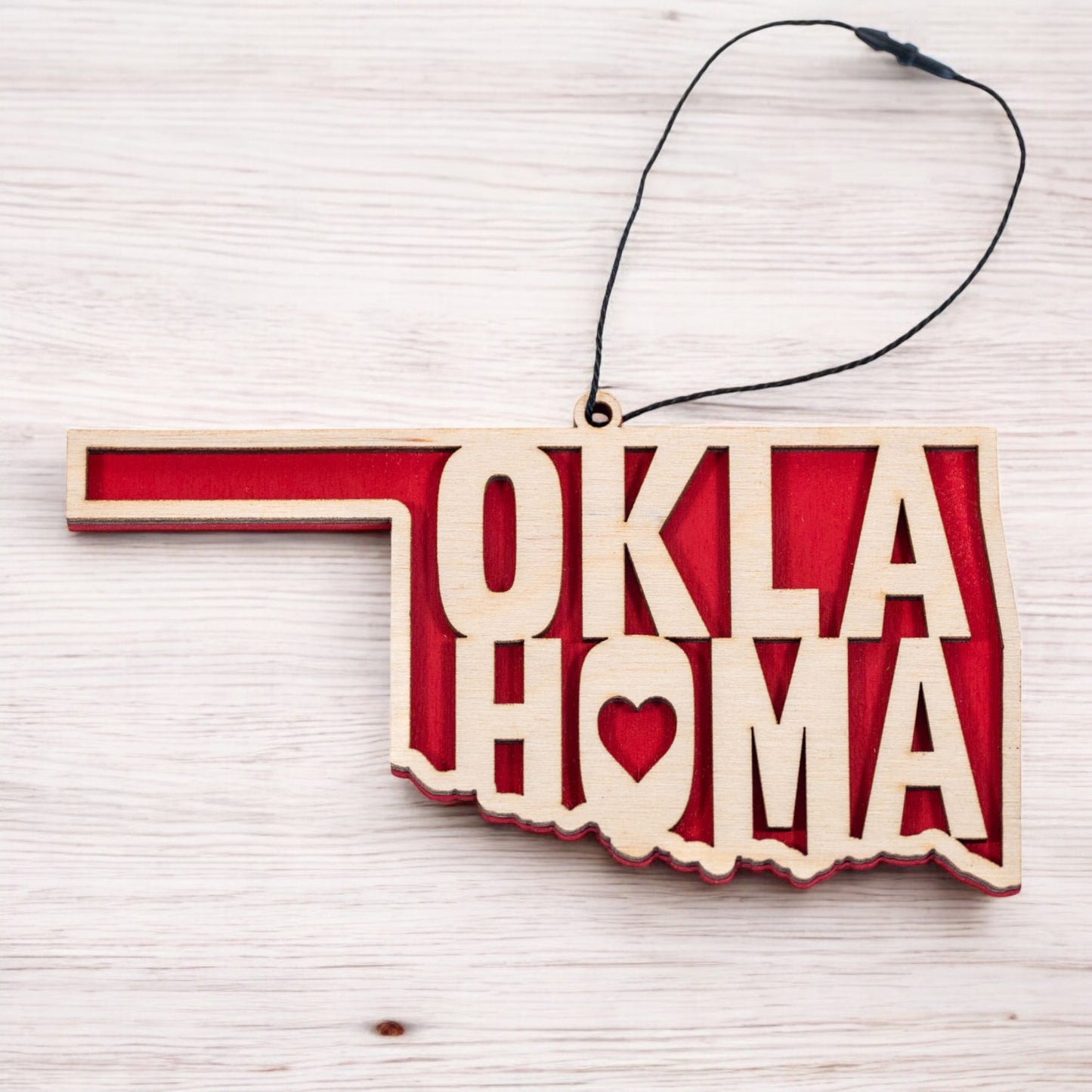 Flat lay of Oklahoma heart wooden ornament showing state outline and heart cutout, layered wood ornament with red backing for Oklahoma decor or gift