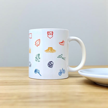 Oklahoma icons coffee mug displayed on wood table, 11oz ceramic mug with repeating Oklahoma symbol artwork for travel or Route 66 gift
