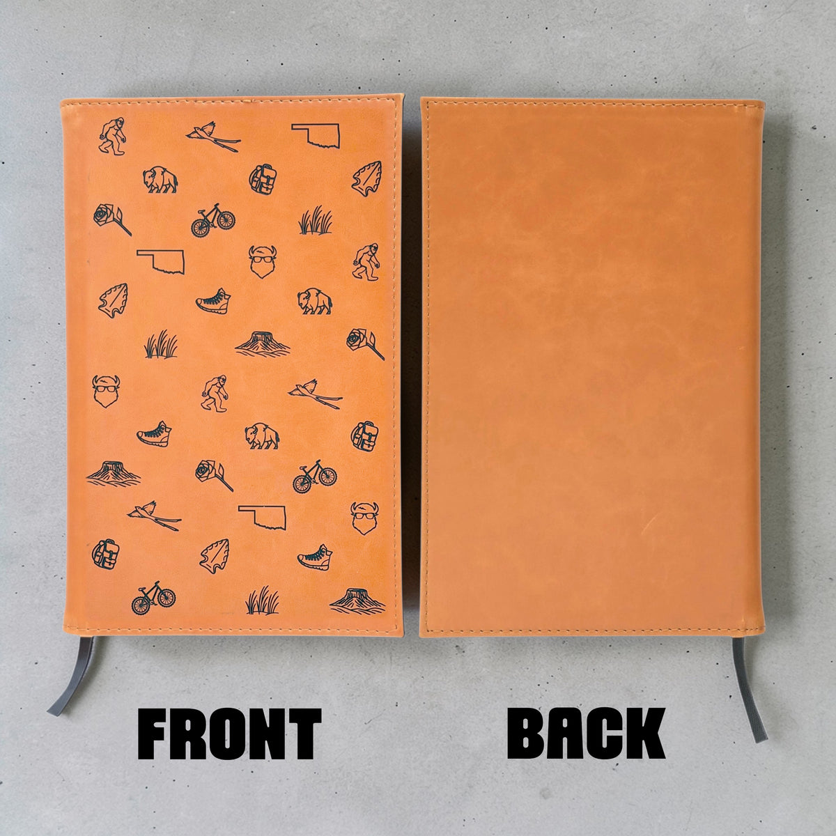 Front and back view of tan leatherette Oklahoma journal showing engraved Oklahoma icon pattern on front, plain back cover and black ribbon bookmark