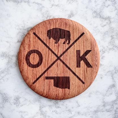 Close up of engraved Oklahoma OK bison design on solid red beechwood round bottle opener magnet, rustic Oklahoma kitchen and bar accessory gift