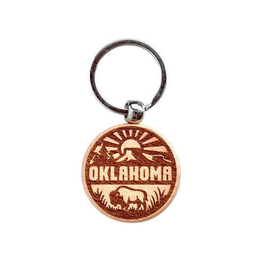 Round Oklahoma outdoor adventure wooden keychain with laser engraved bison, sun rays, mountains, and Oklahoma text, lightweight wood keychain with metal ring for Oklahoma souvenir or Route 66 travel gift made in the USA