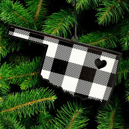 Oklahoma plaid wooden ornament hanging on evergreen tree, state shaped black and white plaid wood ornament used as Oklahoma Christmas decor