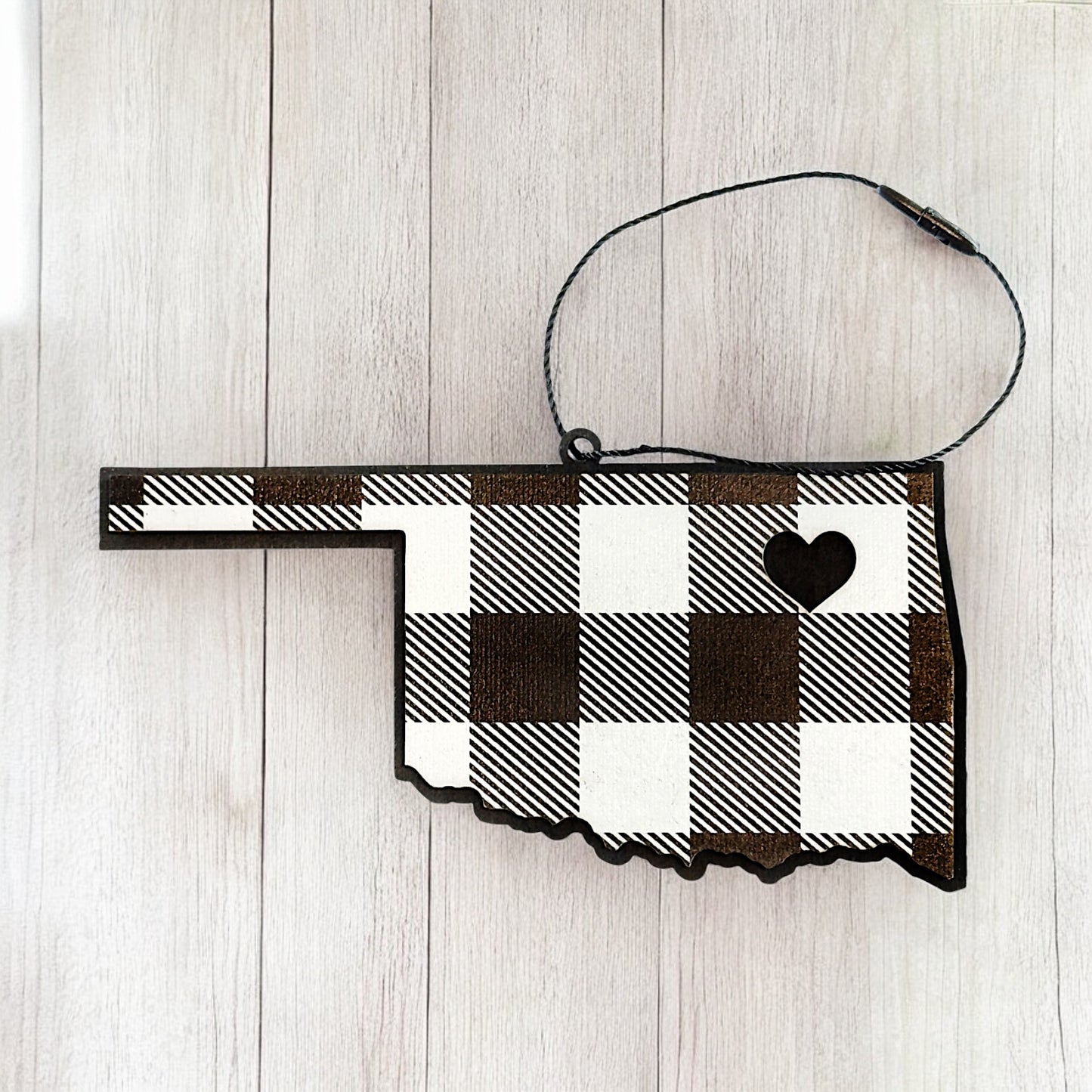 Oklahoma plaid wooden ornament on light background showing state outline, heart cutout, and black hanging cord, minimalist Oklahoma wood ornament