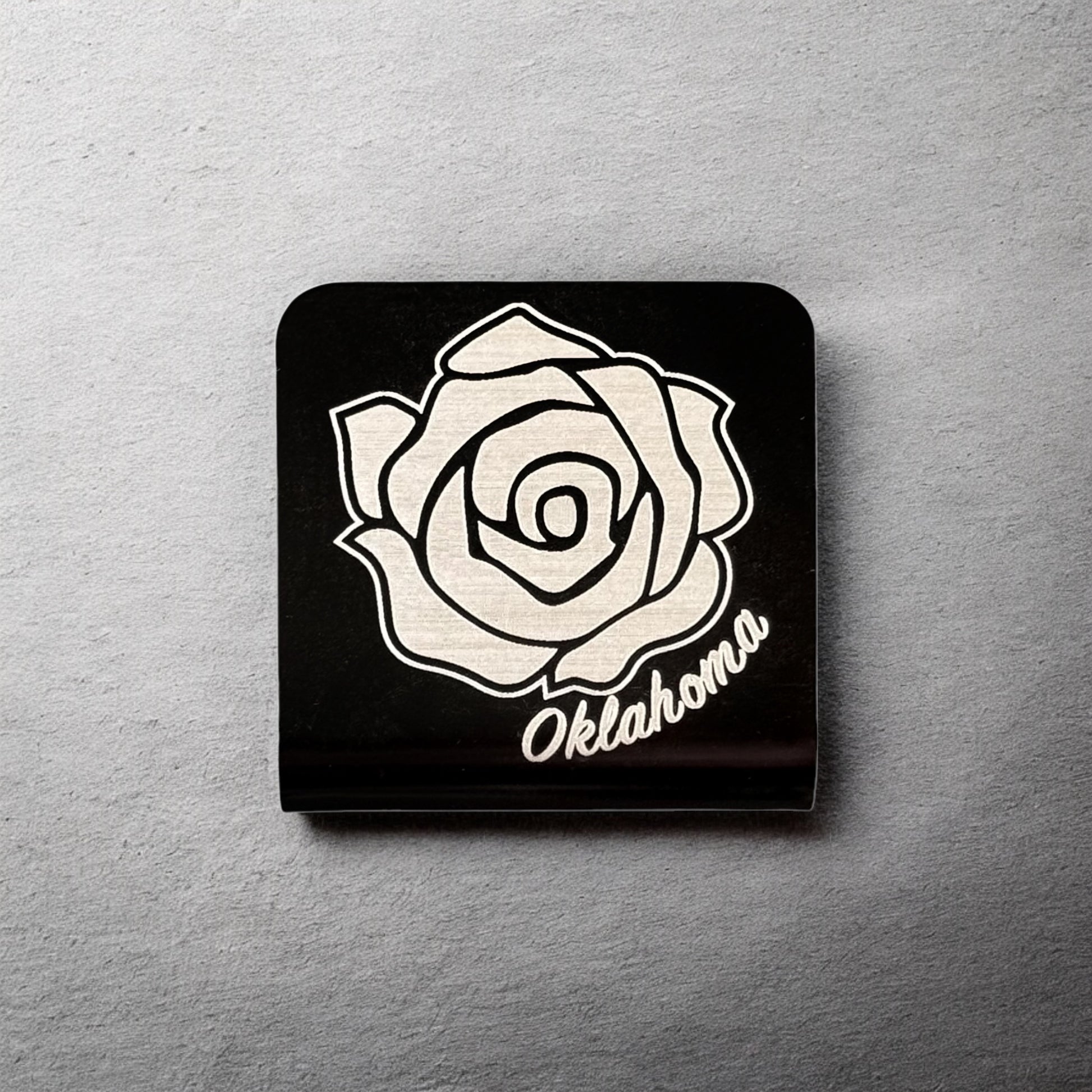 Square aluminum hat clip with Oklahoma rose design displayed against a neutral background showing engraved line detail