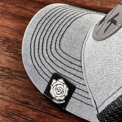Oklahoma rose aluminum hat clip attached to the brim of a gray hat, square black clip with engraved rose design